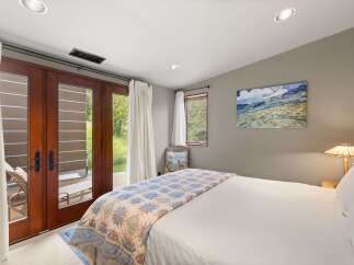 Experience serene living in this charming bedroom, featuring a cozy queen-size bed adorned with a beautiful quilt.