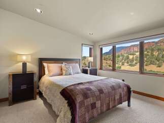 Experience breathtaking mountain views from this serene bedroom, featuring a comfortable queen-size bed adorned with plush pillows and a stylish patterned throw.