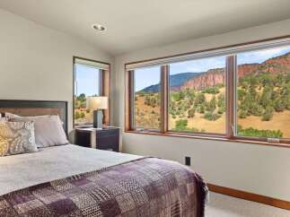 Experience breathtaking mountain views from this serene bedroom, featuring expansive windows that frame the stunning natural landscape.
