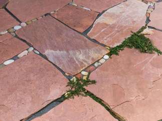 Enhance your outdoor living space with this charming flagstone patio, featuring a unique design with interspersed river stones.