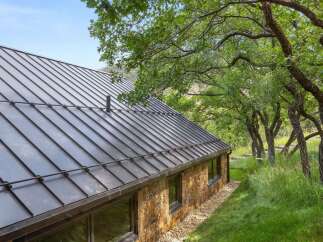 Experience modern rustic living with this stunning home featuring a sleek metal roof and a beautiful stone exterior.