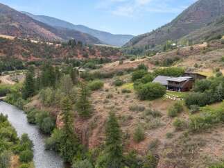 Nestled in a picturesque mountain valley, this stunning property offers a serene retreat with a modern home overlooking a flowing river.