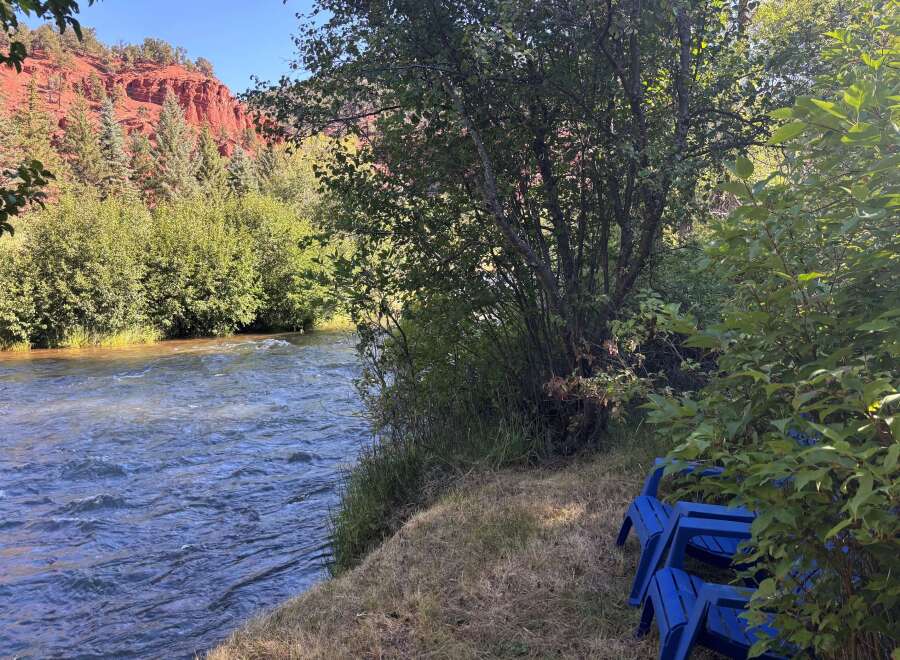 Escape to this serene riverside property, offering breathtaking views of red rock formations and a flowing river.