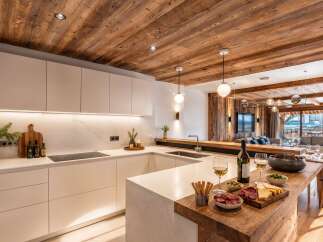Experience luxury mountain living in this stunning modern kitchen, featuring sleek white cabinetry, integrated appliances, and a beautiful marble backsplash.