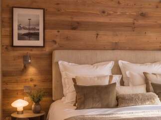 Experience rustic luxury in this beautifully appointed bedroom, featuring a cozy king-size bed adorned with plush pillows and a textured throw.