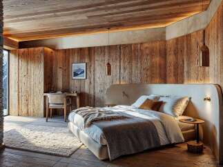 Experience rustic luxury in this mountain retreat bedroom, featuring a cozy bed adorned with plush linens and a textured throw.