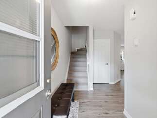 Step into this welcoming entryway featuring a stylish dark brown tufted bench and a decorative gold-framed mirror.