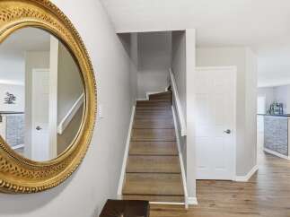 Step into this inviting entryway featuring a grand ornate mirror and a carpeted staircase leading to the upper level.