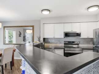This modern kitchen features sleek white cabinetry and a stylish grey subway tile backsplash.