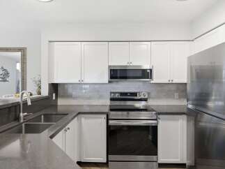 This modern kitchen boasts sleek stainless steel appliances, including a microwave and a Samsung refrigerator, complemented by white cabinetry and a stylish subway tile backsplash.