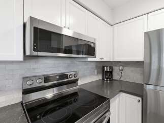 This modern kitchen features sleek stainless steel appliances, including a microwave and a refrigerator, complemented by white cabinetry and a stylish subway tile backsplash.