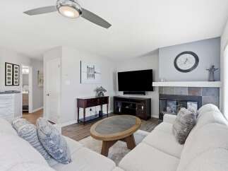 Step into this inviting living room, featuring a cozy fireplace with a slate tile surround and a large TV for entertainment.