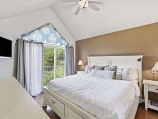 Experience ultimate comfort in this master bedroom, featuring a spacious king-sized bed with crisp white linens and decorative pillows.