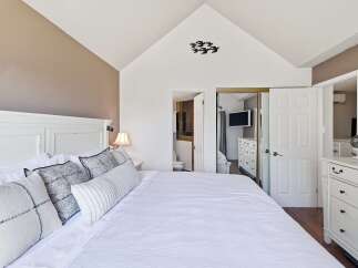 Experience comfort and style in this master bedroom featuring a vaulted ceiling and a serene color palette.