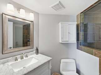 This modern bathroom features a sleek vanity with a marble countertop and a vessel sink, complemented by a brushed nickel faucet.