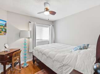 This charming bedroom features a comfortable queen-size bed with a plush white comforter and a decorative blue and white accent pillow.