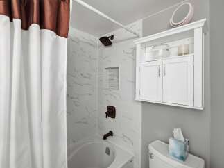 This bathroom features a clean and modern aesthetic with white subway tile and marble-look accents in the shower.