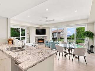 Experience modern living in this stunning open-concept space, featuring a sleek kitchen with granite countertops and a double sink, flowing seamlessly into a bright living area with a cozy fireplace.