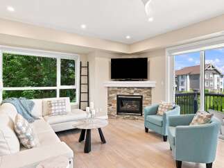 Experience modern living in this beautifully appointed living room, featuring a cozy fireplace with a stone accent and a large flat-screen TV.