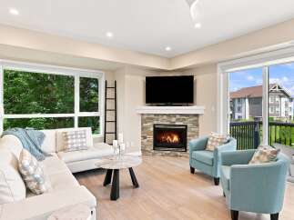 Experience modern living in this beautifully appointed living room, featuring a cozy fireplace with a stone accent and a large flat-screen TV.