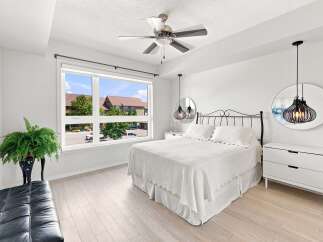 Experience modern comfort in this bright bedroom, featuring a plush white bed and elegant black metal headboard.