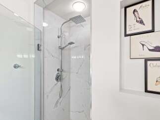 Experience luxury in this modern bathroom featuring a sleek shower with dual showerheads and elegant marble tilework.