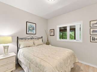 This charming bedroom features a comfortable queen-size bed with a decorative headboard, complemented by a matching nightstand and lamp.