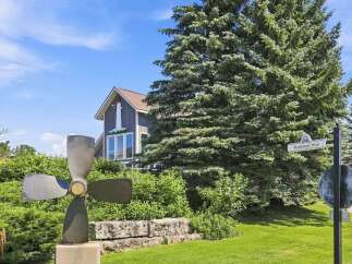 Discover this charming property featuring a unique nautical-themed house with a lighthouse accent, set against a backdrop of lush greenery and mature trees.