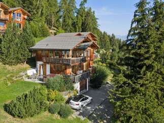 Experience luxury mountain living in this stunning wooden chalet, nestled amidst lush greenery and mature trees.