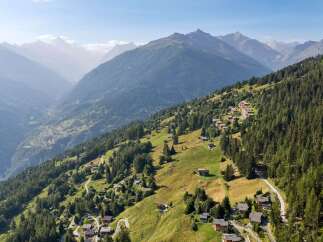 Discover a charming alpine village nestled on a verdant mountainside, offering breathtaking panoramic views of the surrounding peaks and valleys.