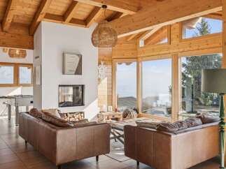 Experience breathtaking mountain views from this stunning chalet living room, featuring a modern fireplace and comfortable leather sofas.