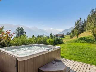 Experience ultimate relaxation with this stunning hot tub, perfectly situated on a wooden deck with breathtaking mountain views.