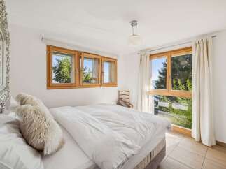 Experience serene mountain living in this charming bedroom, featuring a comfortable bed adorned with plush pillows and a large duvet.