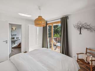 Experience serene living in this charming bedroom featuring a comfortable bed, a modern ensuite bathroom, and a private balcony with scenic views.