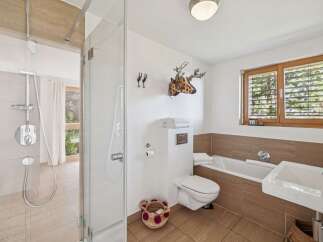 This modern bathroom features a spacious walk-in shower with a rainfall showerhead and a separate bathtub for ultimate relaxation.