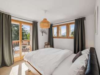 Experience breathtaking mountain views from this charming bedroom, featuring a private balcony perfect for enjoying your morning coffee.