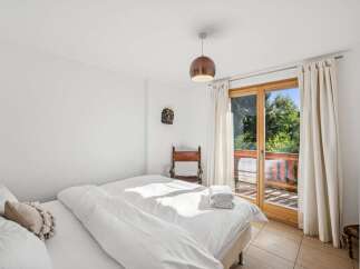 Experience serene living in this charming bedroom, featuring a comfortable bed adorned with crisp white linens and a decorative accent pillow.