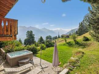 Experience ultimate relaxation with this stunning mountain view property, featuring a luxurious hot tub on a spacious wooden deck.