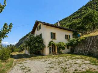Nestled against a lush green mountainside, this charming house offers a serene retreat with stunning natural views.