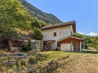Nestled against a lush mountainside, this property offers a unique blend of rustic charm and potential.