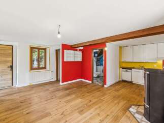 Discover this charming property featuring a bright living area with a rustic wooden door and a large window.
