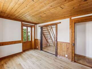Experience rustic charm in this inviting room featuring warm wooden paneling and a beautifully finished wood-plank floor.