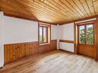 Experience rustic charm in this beautifully appointed room featuring warm wooden paneling on the walls and ceiling, complemented by a light-colored wood floor.