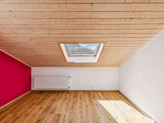 Experience modern living in this beautifully designed room featuring a sloped, wood-paneled ceiling and a striking magenta accent wall.