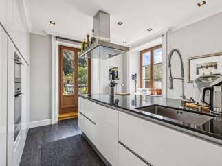 Experience modern luxury in this stunning kitchen, featuring sleek white cabinetry and a spacious black granite island.