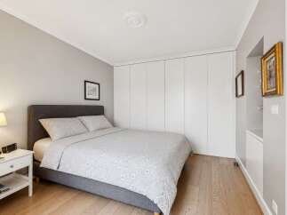 This bedroom features a comfortable grey upholstered bed with a light grey floral duvet and matching pillows.