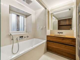 This modern bathroom features a sleek bathtub with a handheld showerhead and a built-in window for natural light.