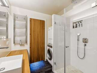 Experience modern convenience in this stylish bathroom featuring a stacked washer and dryer, perfect for maximizing space.