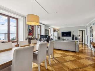 Experience elegant living in this spacious apartment featuring a large dining area with a wooden table and upholstered chairs, perfect for hosting.