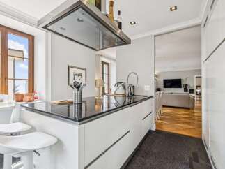 Experience modern living in this stunning kitchen featuring sleek white cabinetry and a glossy black countertop.